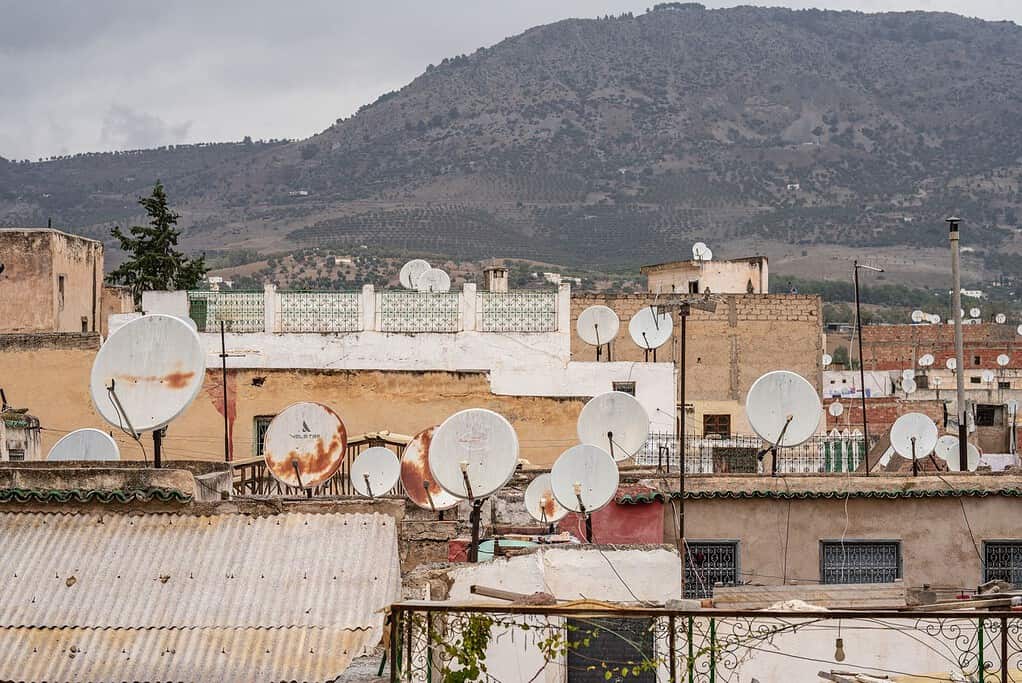 Toits d'une médina marocaine hérissés de paraboles, montagnes en arrière-plan