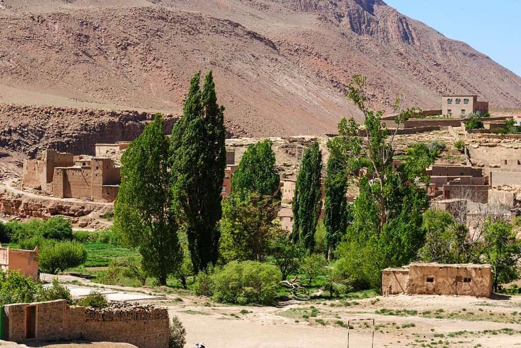 Village berbère au creux d'une vallée de l'Atlas marocain, montagne nue au-dessus