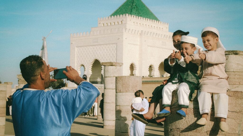 Homme photographiant des enfants avec son téléphone devant le mausolée Mohammed V à Rabat